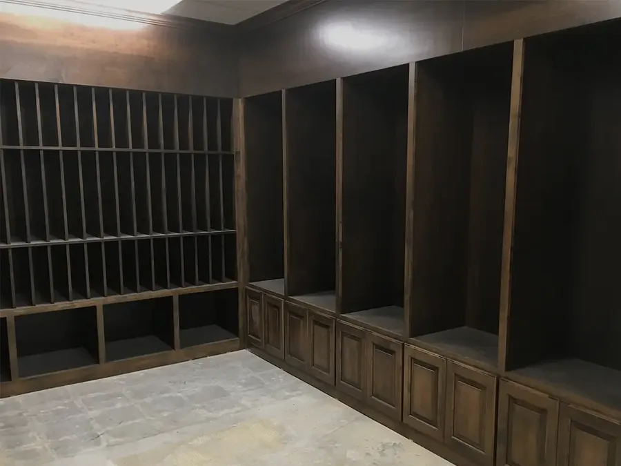 Room lined with dark stained wood cubbies, open lockers, and raised-panel base cabinets