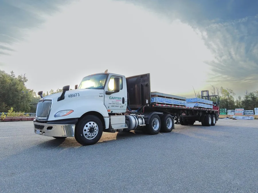 Carter Lumber flatbed truck loaded with materials in a lumber yard at sunrise