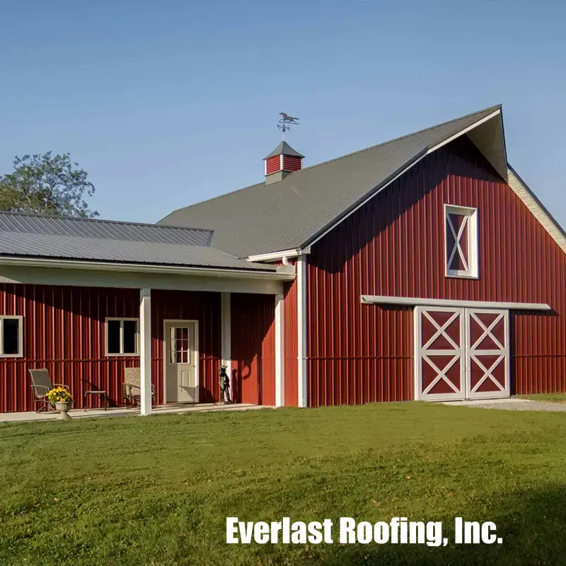 Red metal-sided barn with gray metal roof and cupola, with Everlast Roofing logo