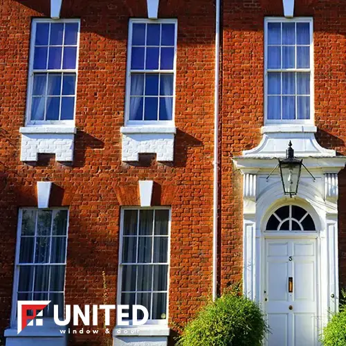 Red brick house with white double-hung windows and a white front door with fanlight