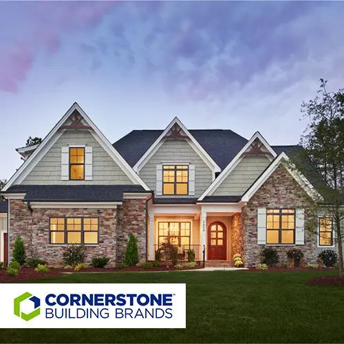Craftsman-style stone and shake-sided home at dusk with Cornerstone Building Brands logo