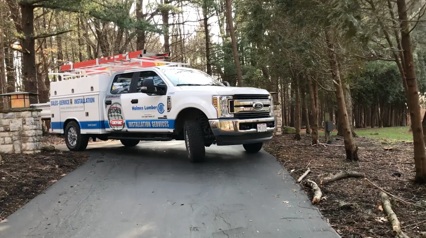 Holmes Lumber installation services pickup truck parked on a wooded driveway