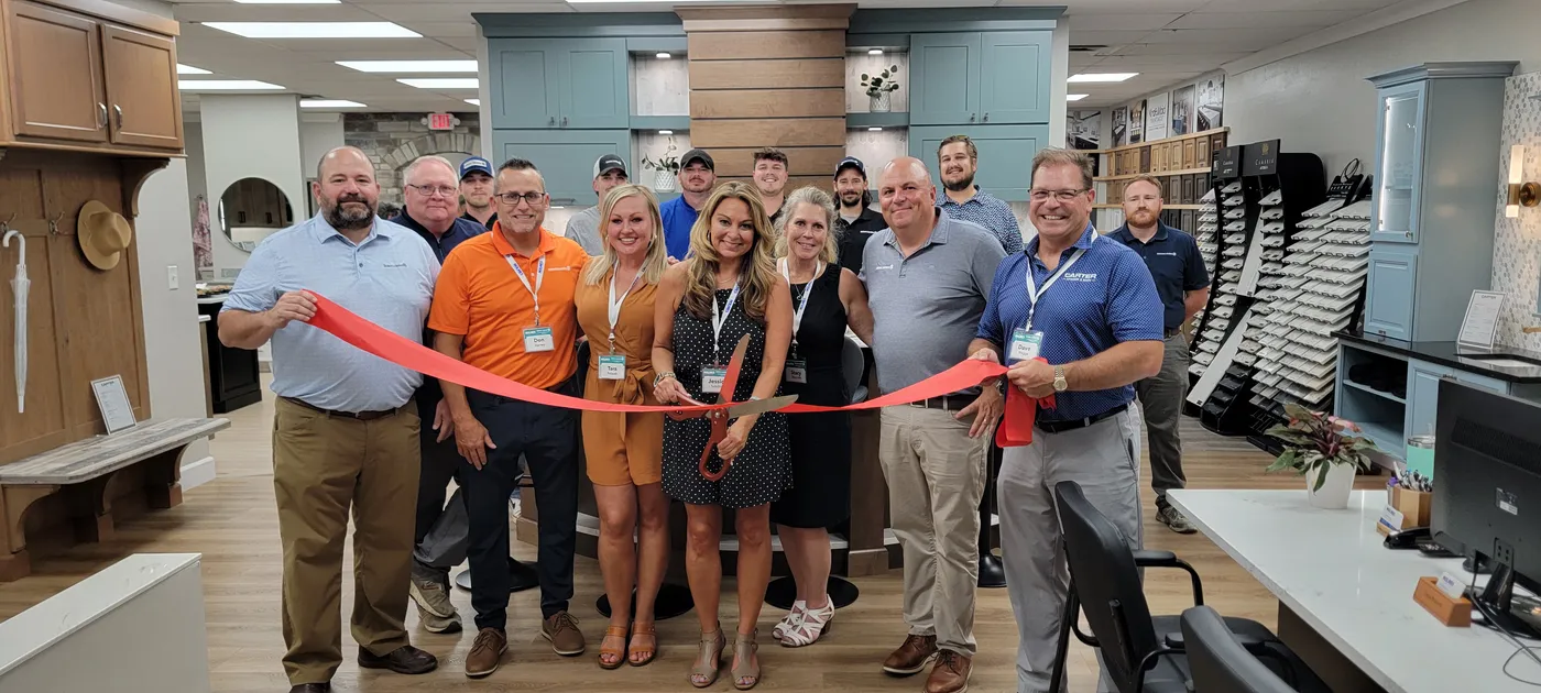 Group cutting a red ribbon at a kitchen and bath showroom grand opening