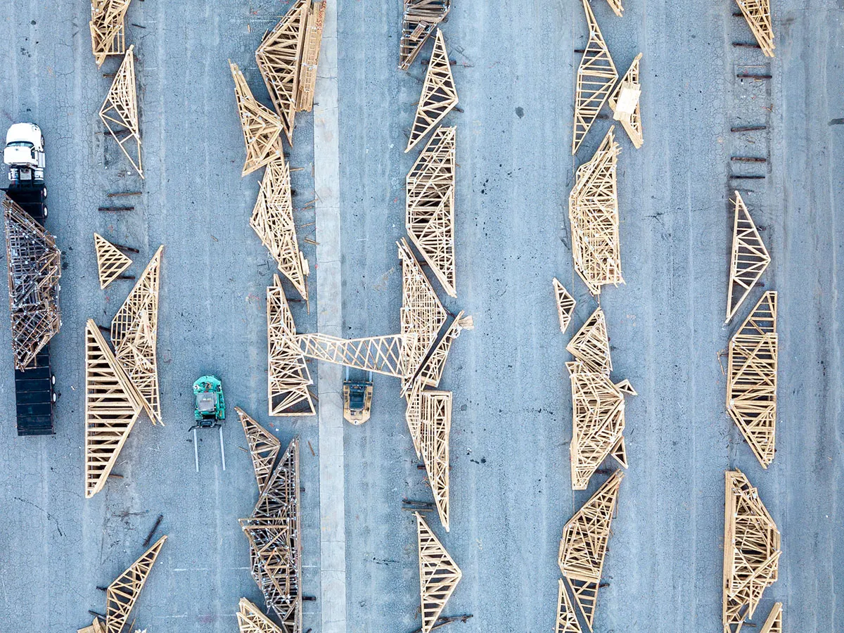 Overhead view of finished roof trusses laid out in rows on a paved yard