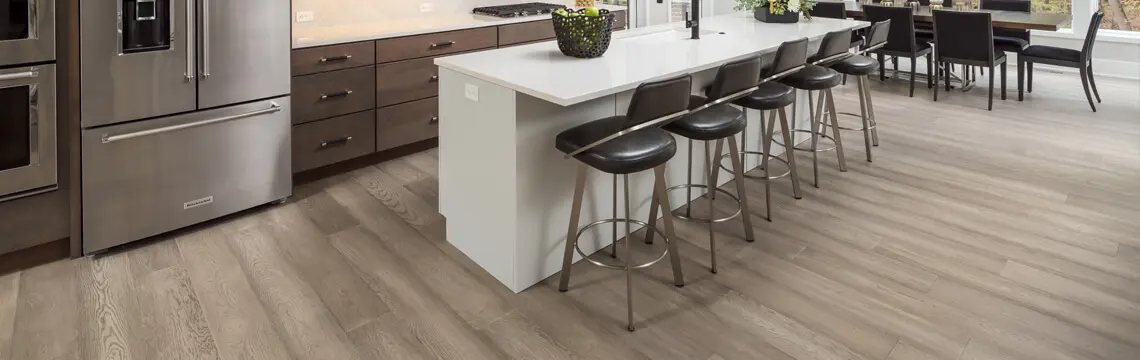 Gray wood-look plank flooring in an open kitchen with island bar stools