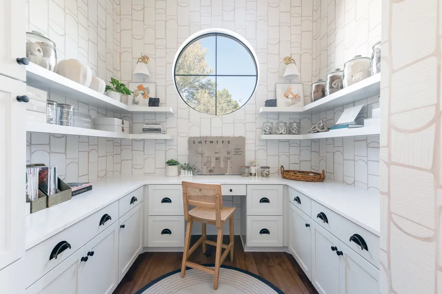 Bright butler's pantry with white cabinets, open shelves, and a round window