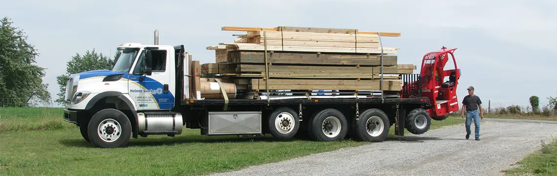 Holmes Lumber flatbed truck loaded with lumber and a truck-mounted forklift